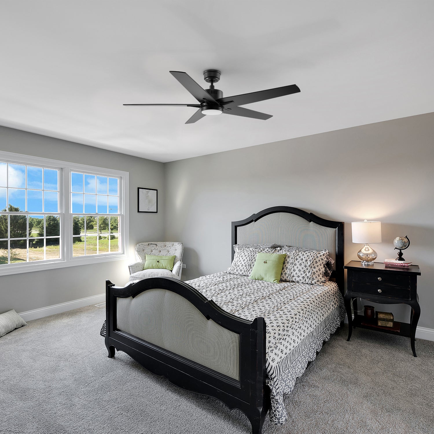 A modern 52-inch ceiling fan with a built-in LED light, featuring five reversible blades in a dark wood finish. Installed in a traditional bedroom with a black wood bed frame, neutral decor, and natural lighting.