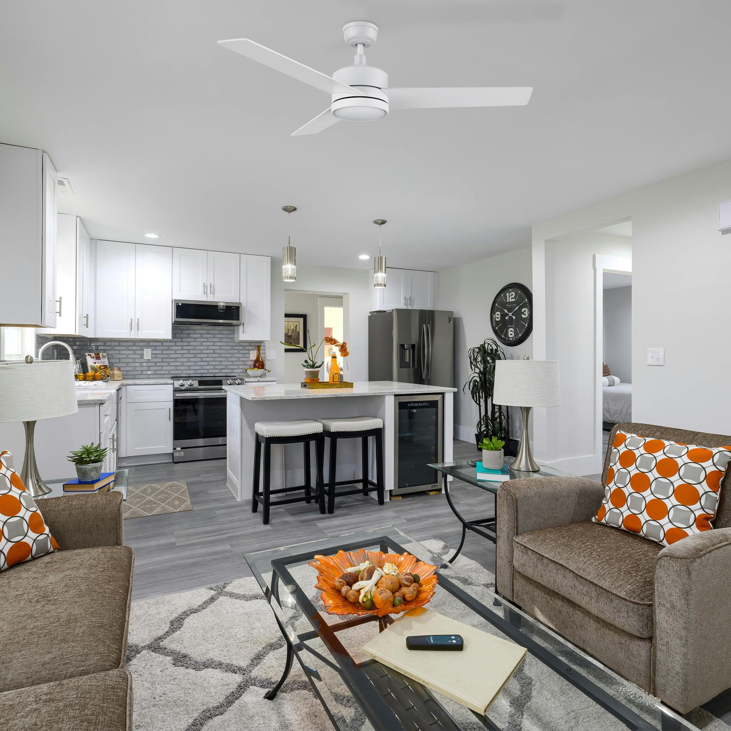 52-inch Louy modern white ceiling fan with integrated LED light and wall switch, installed in a bright, open-concept living room and kitchen featuring neutral tones and contemporary decor.