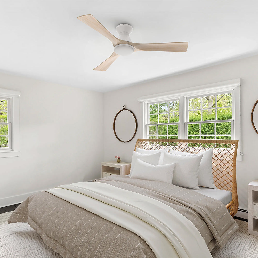 White flush mount 3-blade wood ceiling fan with LED light installed on the ceiling of a bright modern bedroom.