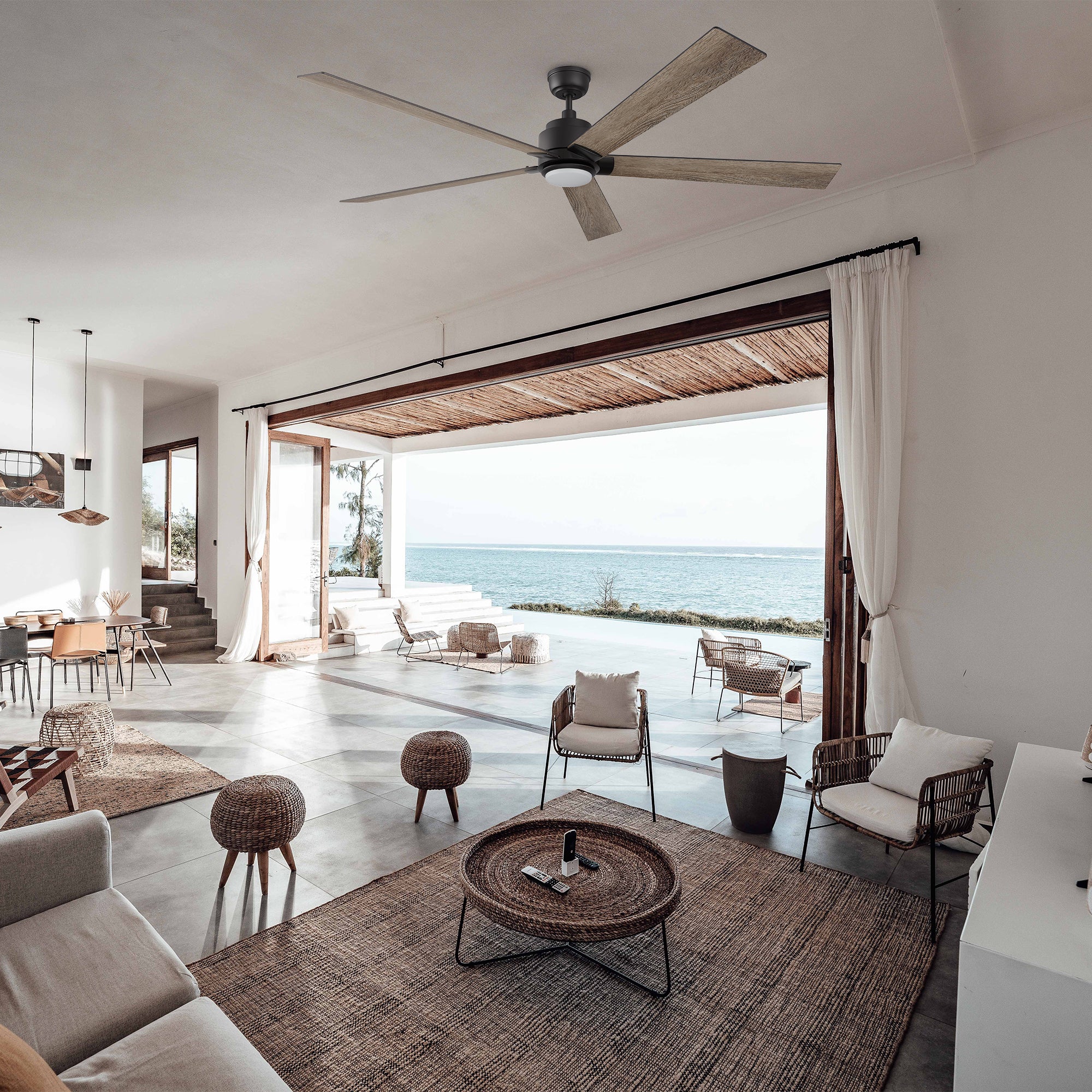 Coastal living room with open ocean views, featuring the Aspen smart ceiling fan in a 70-inch size, blending seamlessly into the airy, contemporary design.