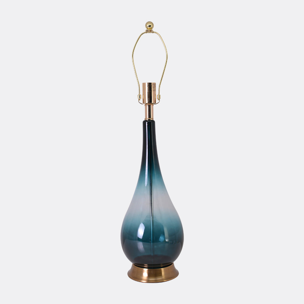 A close-up of a Carro Smafan 30-inch Tulip Big table lamp with a Dark Green Ombre finish and Translucent Silver shade, illuminating a corner with a soft glow. The lamp&