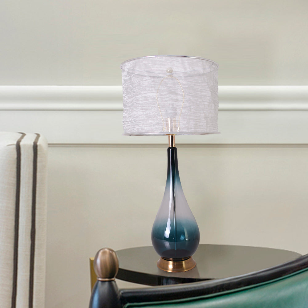 A side table view of a Carro Smafan 30-inch Tulip Big table lamp with a Dark Green Ombre finish and Translucent Silver shade, measuring 30 inches in height and 14 inches in width. The lamp is placed on a dark wooden table, complementing the room&
