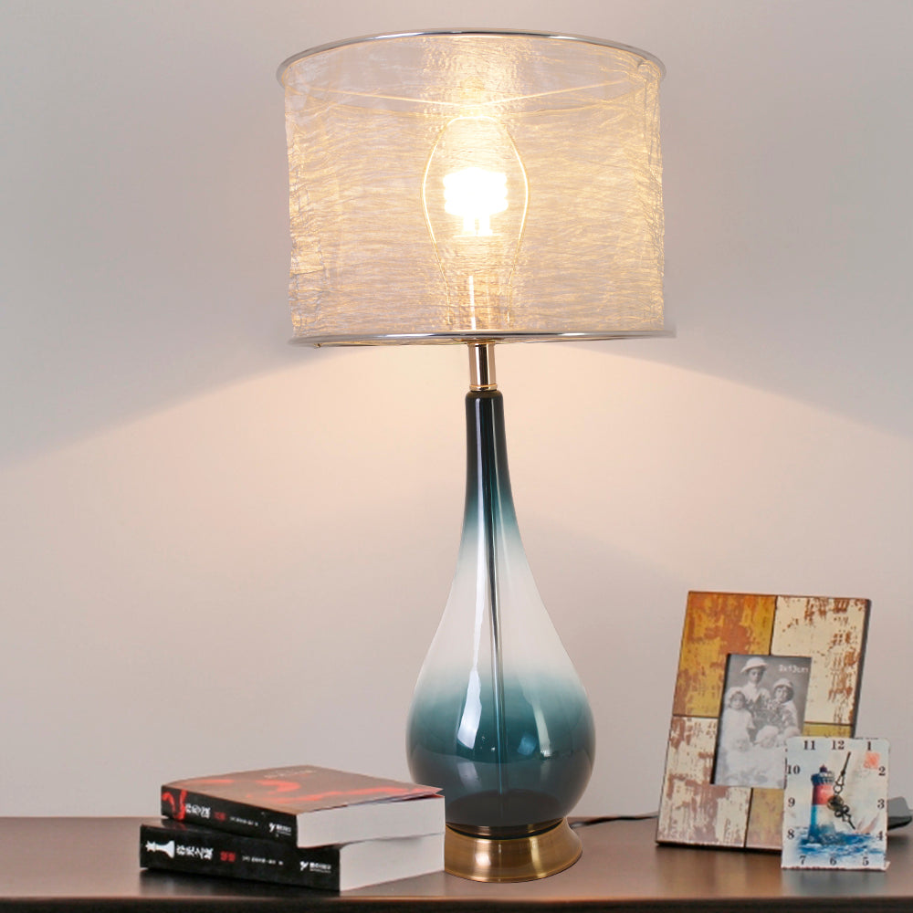 A second side table view of a Carro Smafan 30-inch Tulip Big table lamp with a Dark Green Ombre finish and Translucent Silver shade, placed on a wooden table. The lamp is shown illuminating a corner with books and decor, highlighting its lighting functionality and stylish design.