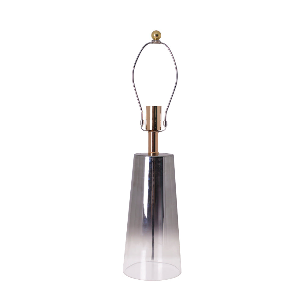 A close-up of a Carro Smafan Rosemary Table Lamp, 25 inches tall, with a Chrome Grey Ombre finish and white shade, illuminating a corner with a soft glow. The lamp&