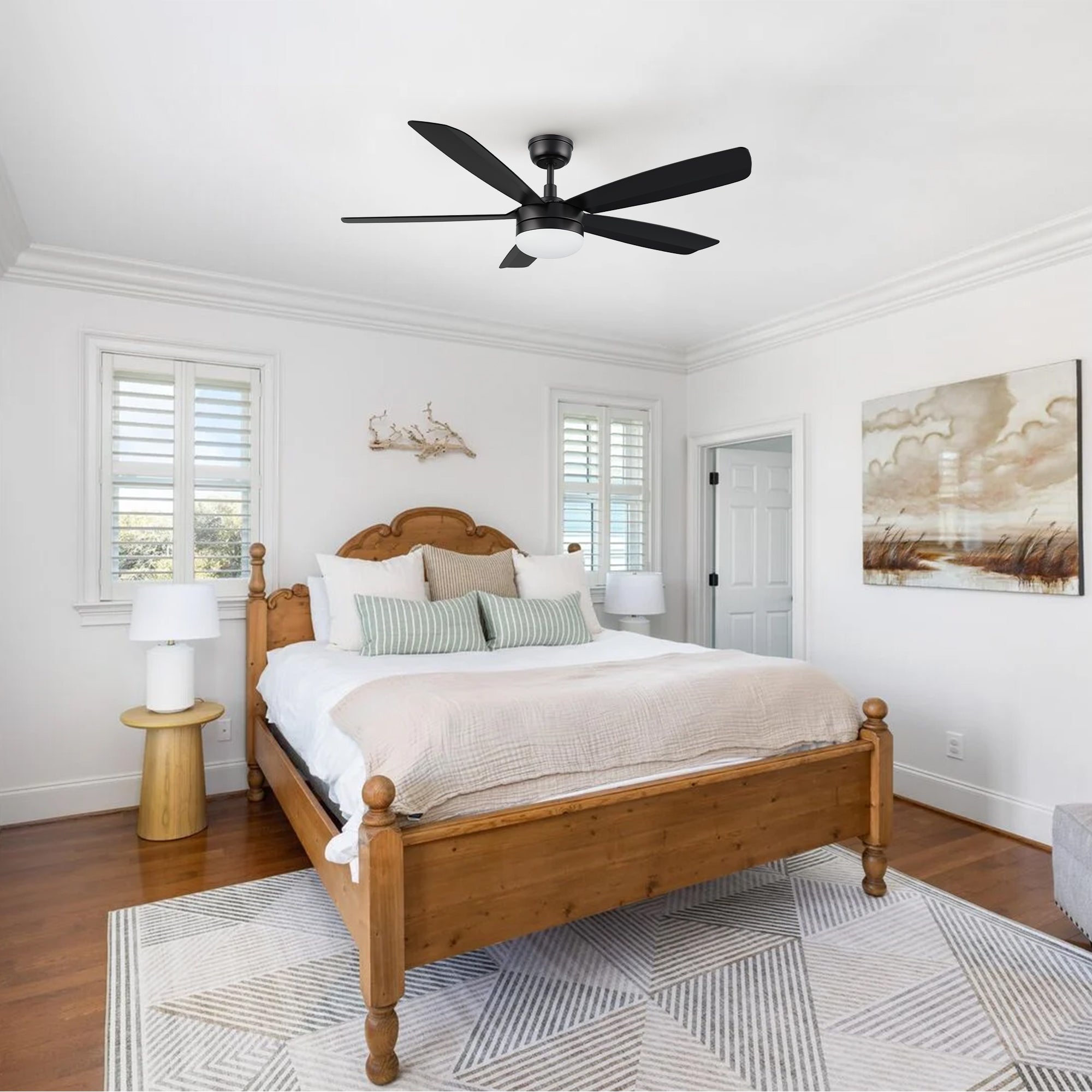 A stylish 52-inch black ceiling fan with a central light fixture installed in a modern bedroom with minimalist decor, featuring a low platform bed and large windows.