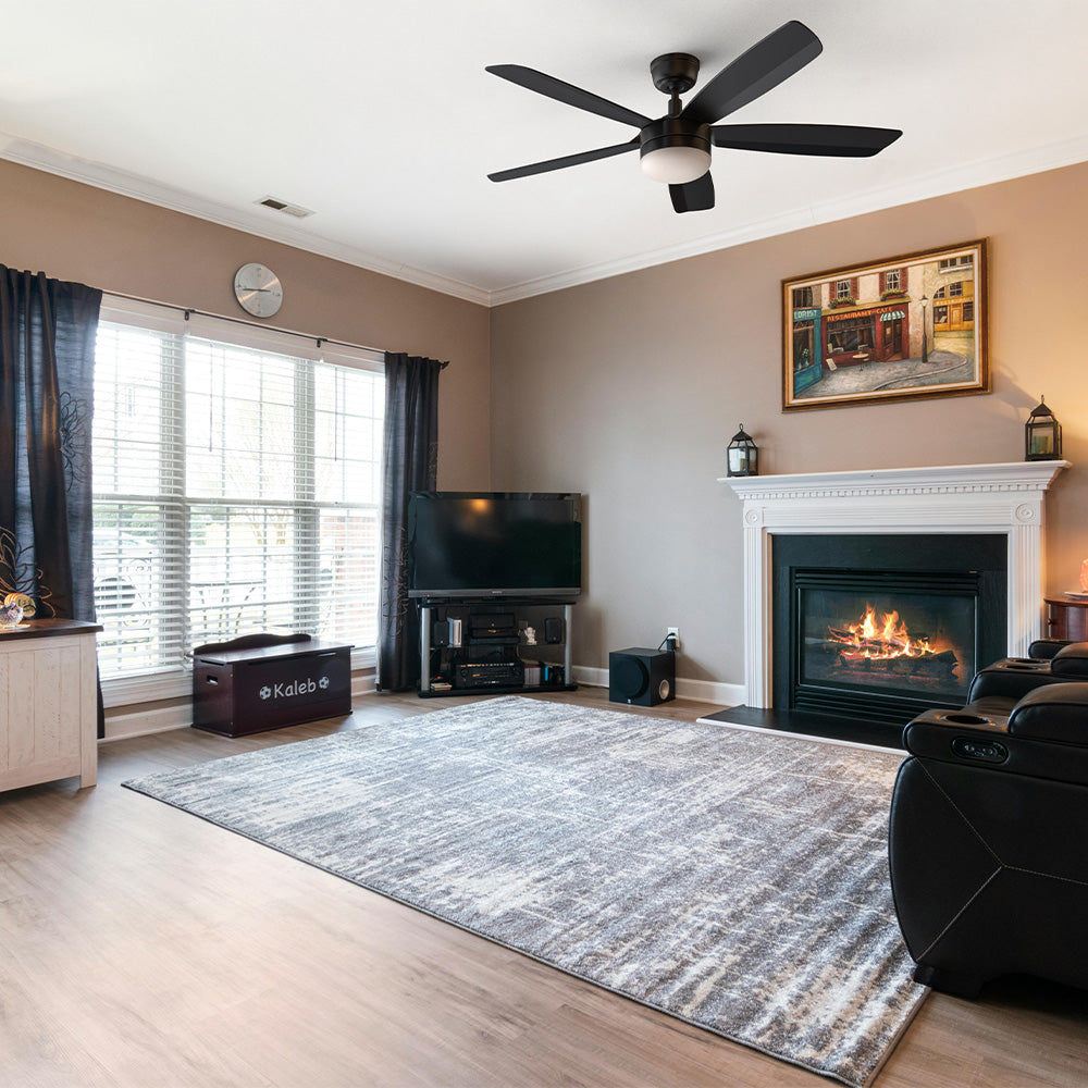 A 52-inch black ceiling fan with LED light, installed in a contemporary living room with modern furniture and large windows, from the Carro Smafan Rivers collection.