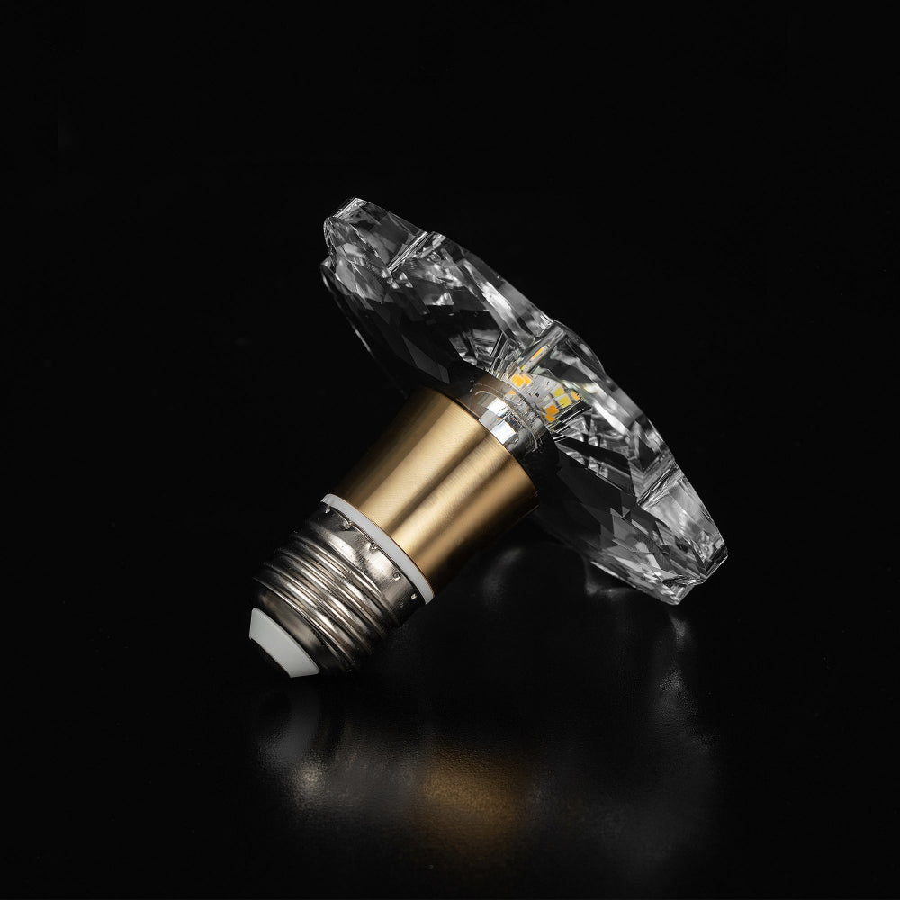 Clear crystal LED bulb with a faceted flower shape and a brushed gold metal collar, shown in a bottom-angled product shot.