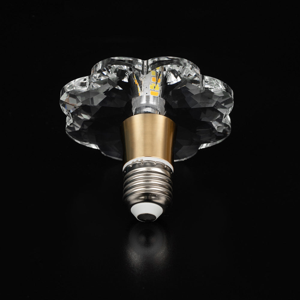 Clear crystal LED bulb with a multi-faceted flower shape and a brushed gold metal collar, captured in a straight bottom-up view.