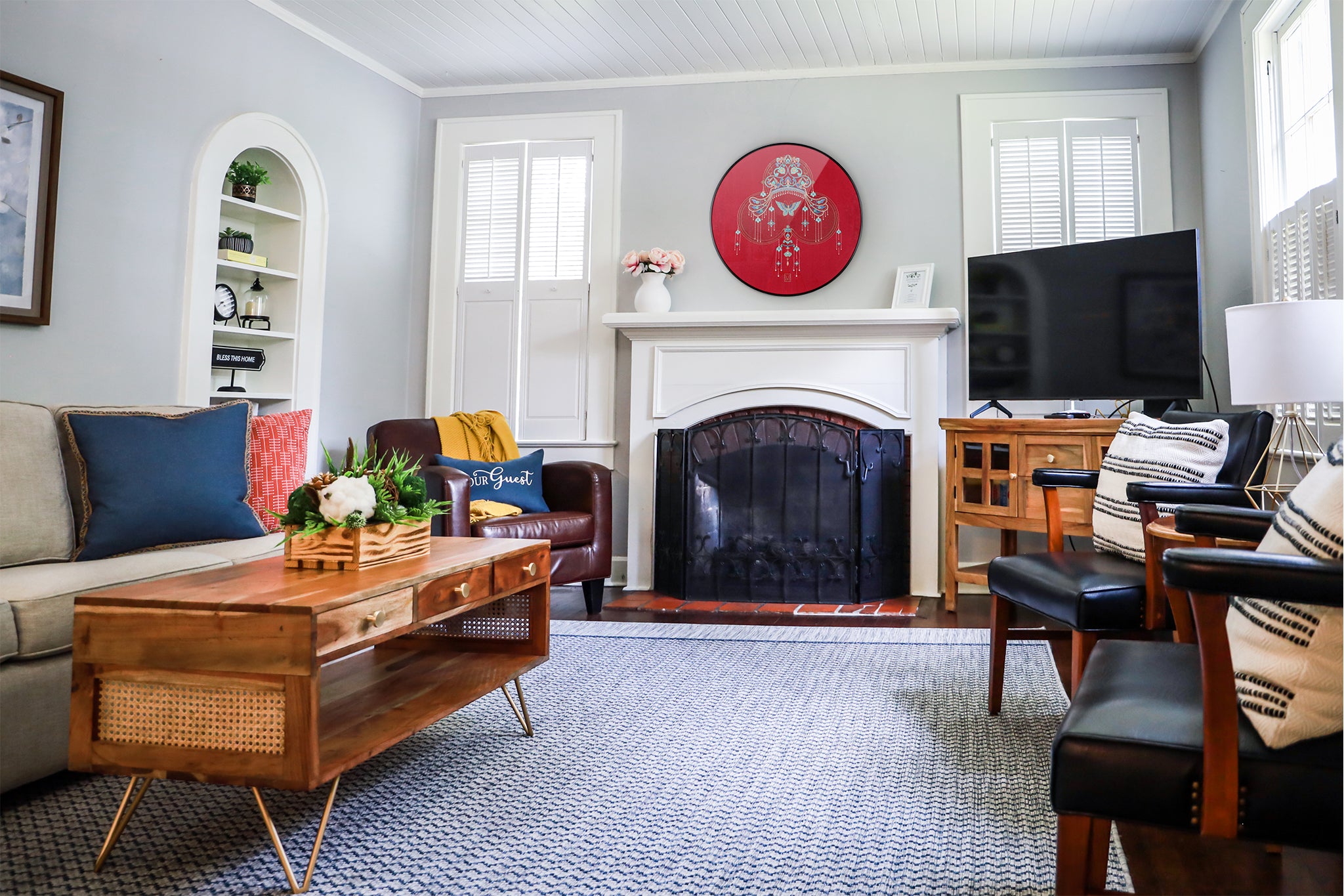 An embroidered wall artwork of a phoenix crown is placed above the fireplace in the modern living room.