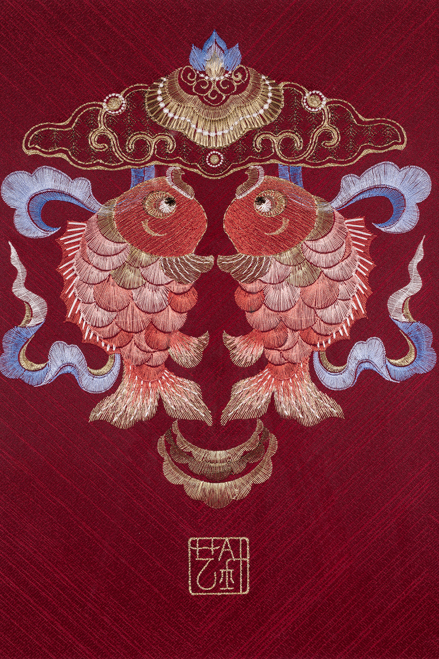 An embroidered artwork with two koi carp hangs on the wall as a home decoration.