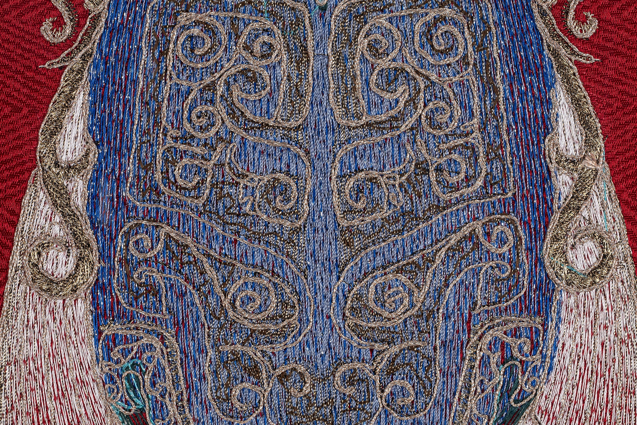 Close-up of the chest details of a framed embroidery artwork featuring a cicada design. The intricate embroidery showcases detailed patterns in blue and white thread on a red background.