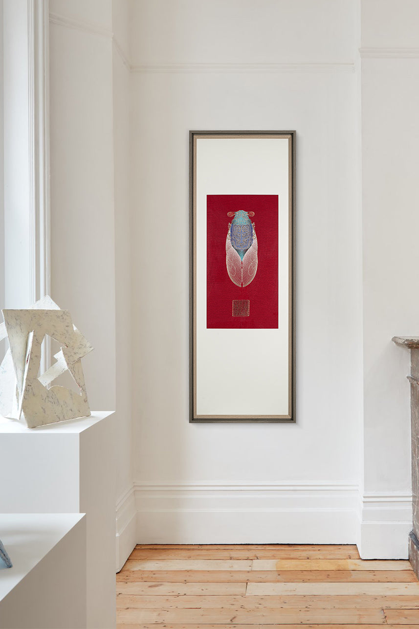 A living room with white walls and a wooden floor. A framed embroidery artwork featuring a cicada design hangs on the wall, enhancing the artistic ambiance of the space.