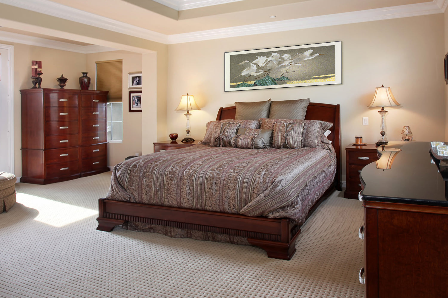 A framed embroidery artwork of egrets displayed above the bed in a spacious bedroom with wooden furniture.