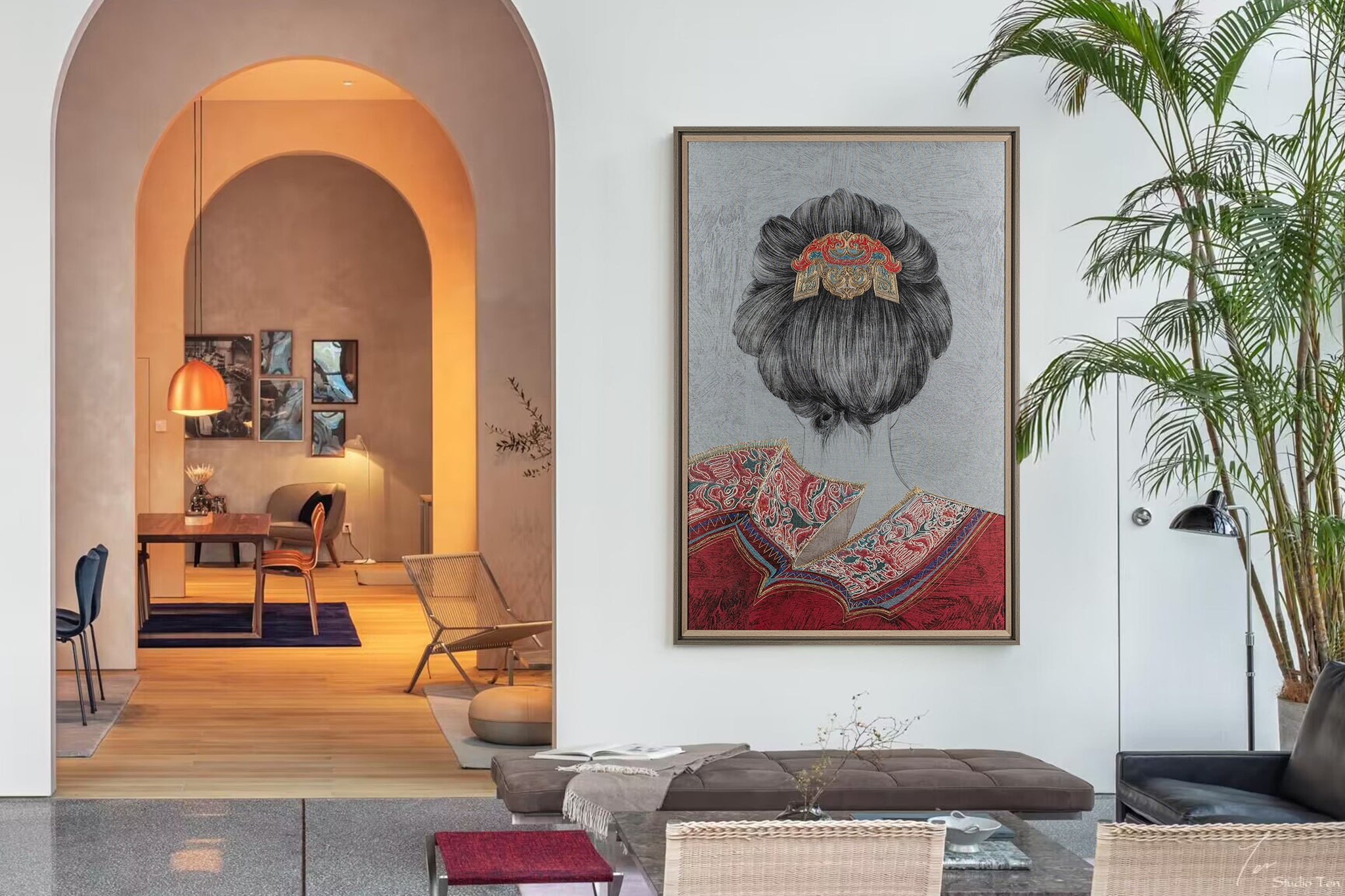 An framed embroidered work of art with the back of a female figure hangs on the reception wall of an art studio.