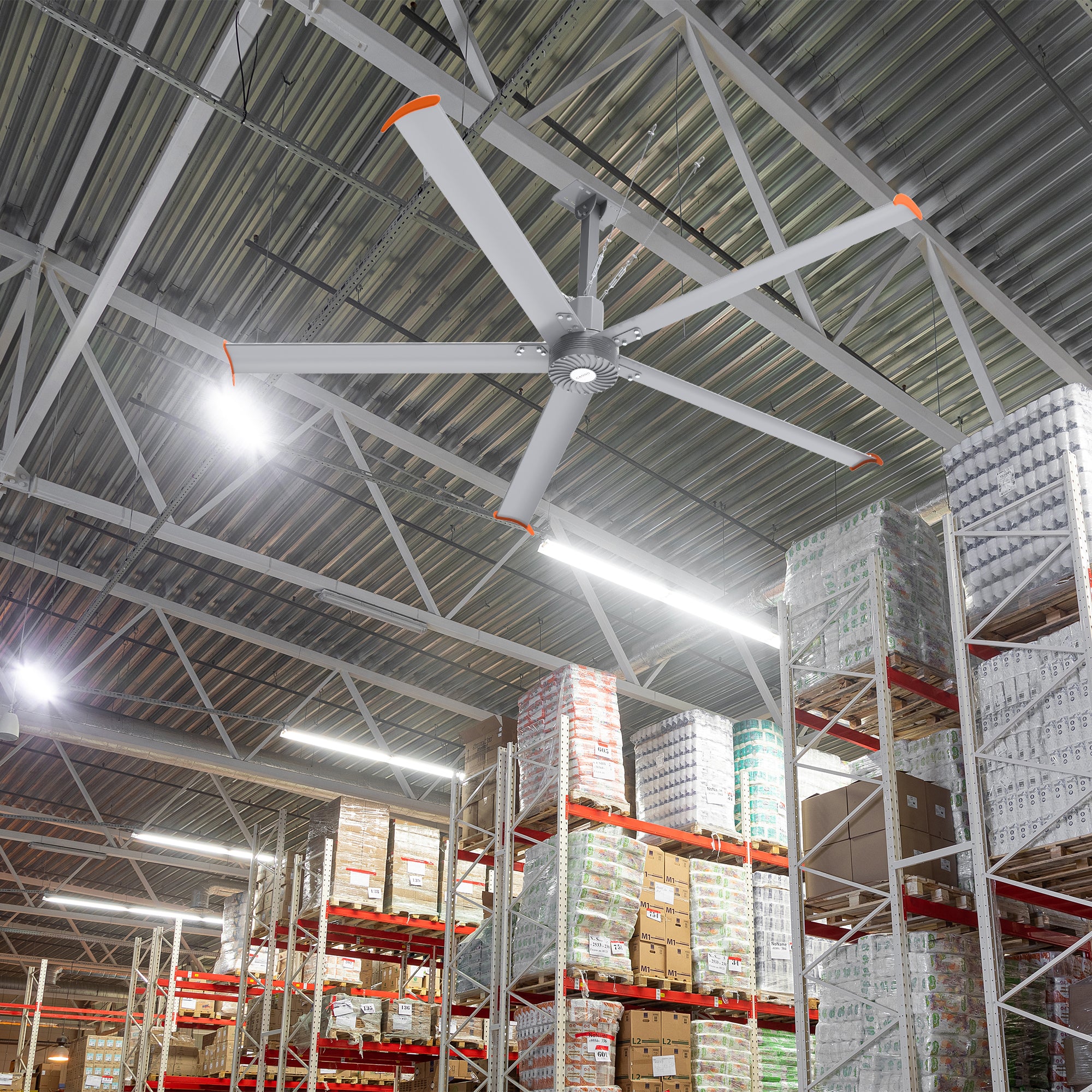 Makani 10ft industrial HVLS fan in a warehouse setting, providing optimal air movement among tall shelves stocked with various goods and creating a comfortable working environment for employees.