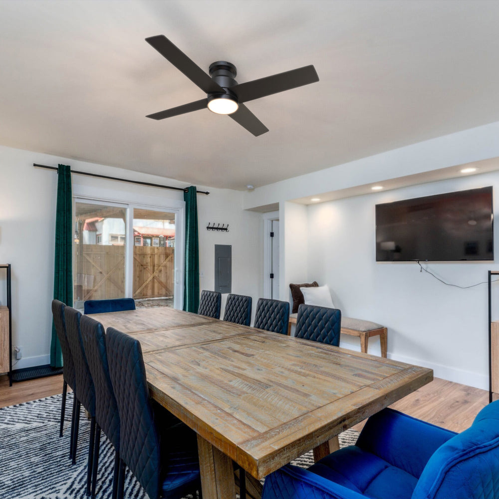 The image shows a modern dining room featuring an Olinda 52-inch Flush Mount Ceiling Fan in matte black. This fan&