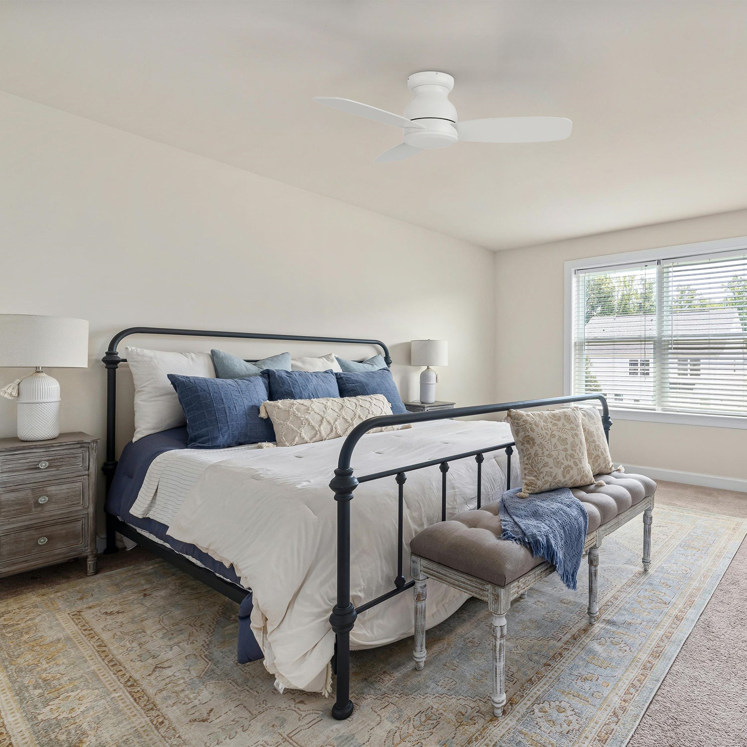 White 44-inch Osborn flush mount ceiling fan installed in a cozy bedroom with a large bed, blue and beige décor, and natural light streaming through windows.