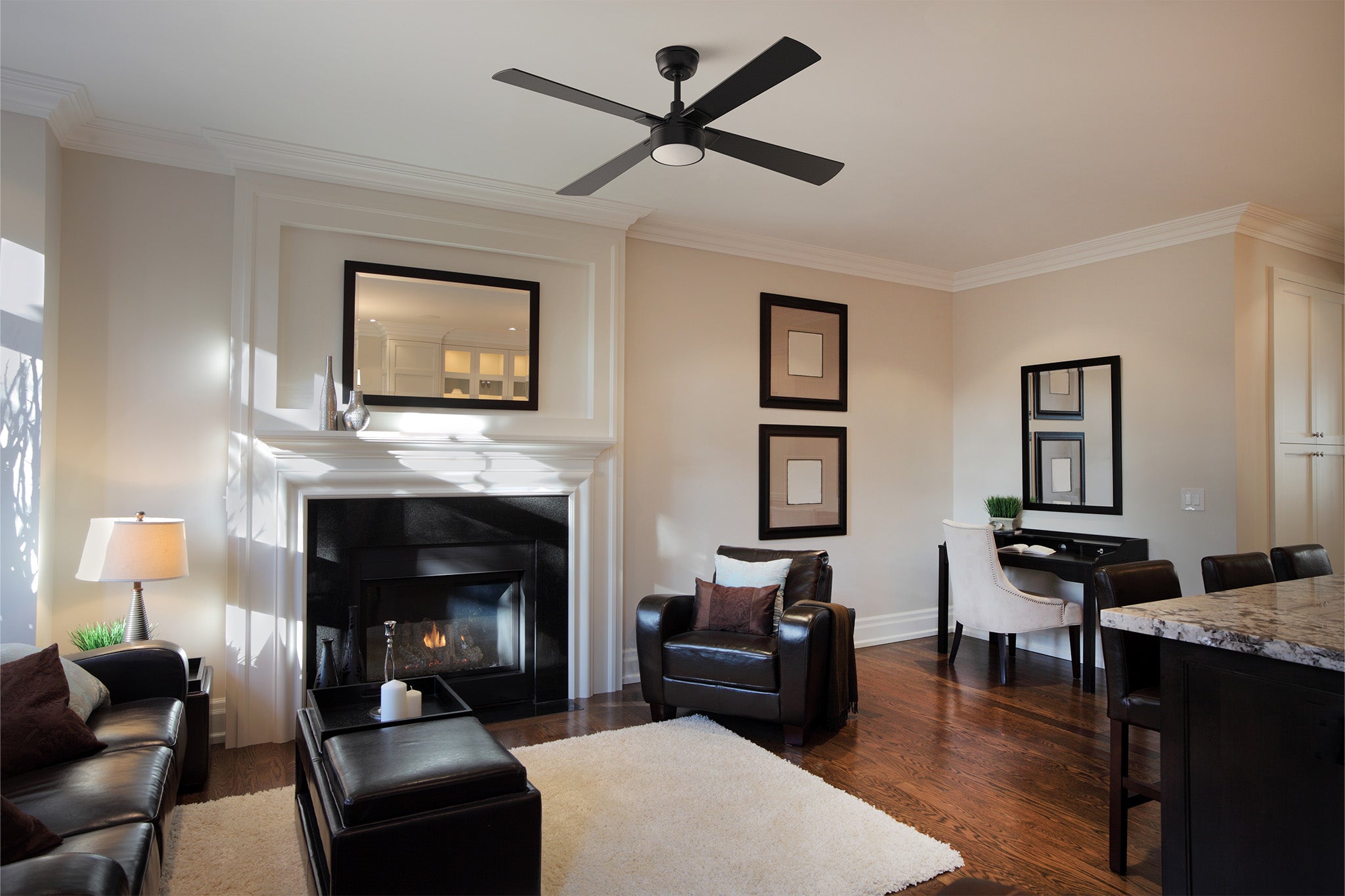 Smafan Admiral 52 inch black ceiling fan with integrated LED light installed in a contemporary living room. The modern fan complements the elegant interior featuring a fireplace, leather seating, dark wood floors, and neutral décor, providing stylish comfort and efficient airflow for a large indoor living space.