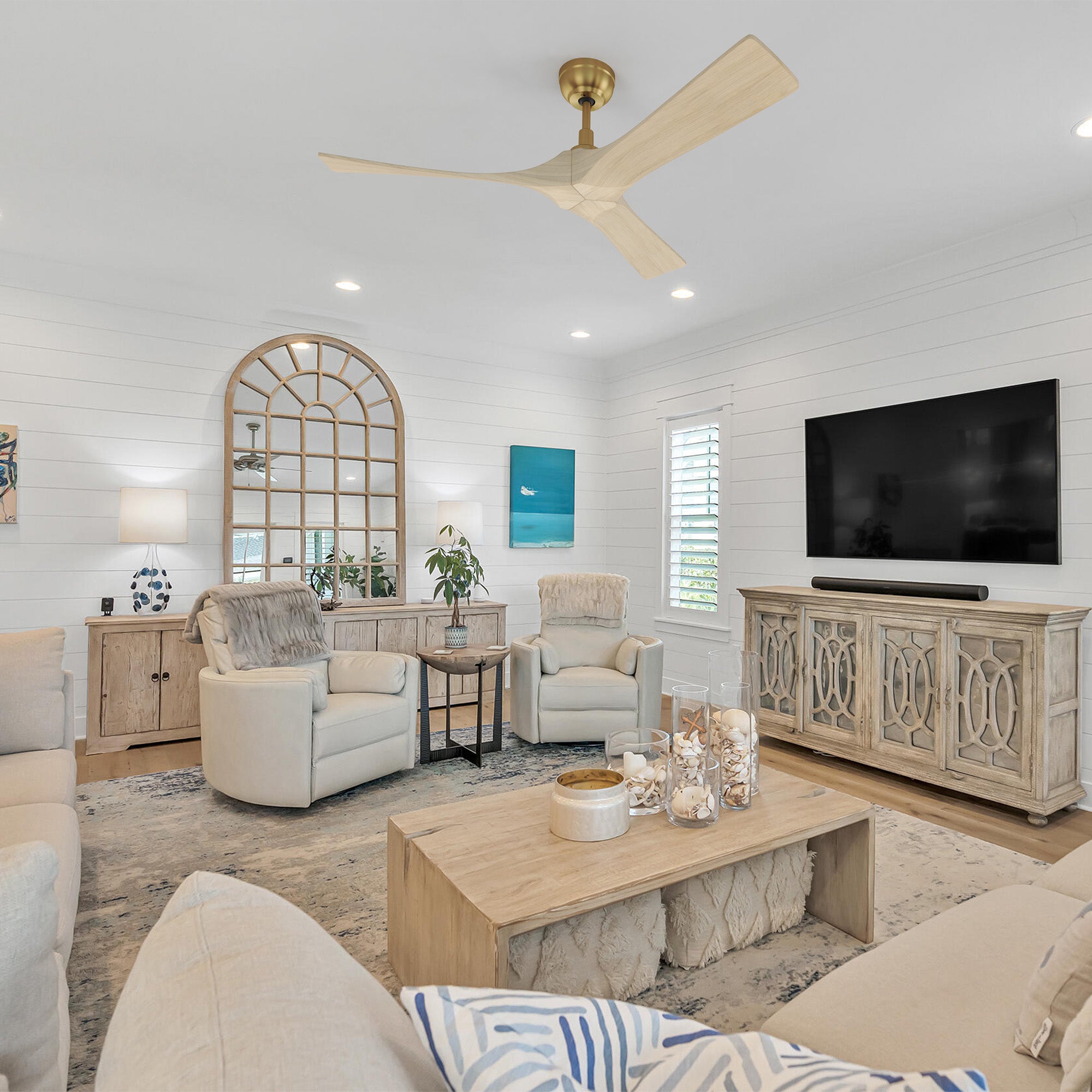 Bright, coastal-style living room with white shiplap walls, neutral furniture, and a 52-inch Smafan Matthews ceiling fan featuring light wood blades and a brass downrod, blending elegance and airflow without a built-in light fixture.