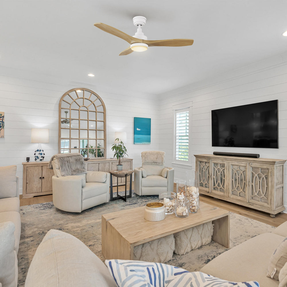 Rustic living room with wood tones, console cabinet, wall-mounted TV, and greenery; Ultiem 48-inch wood fan in white with LED light centered above the seating area for warm illumination.