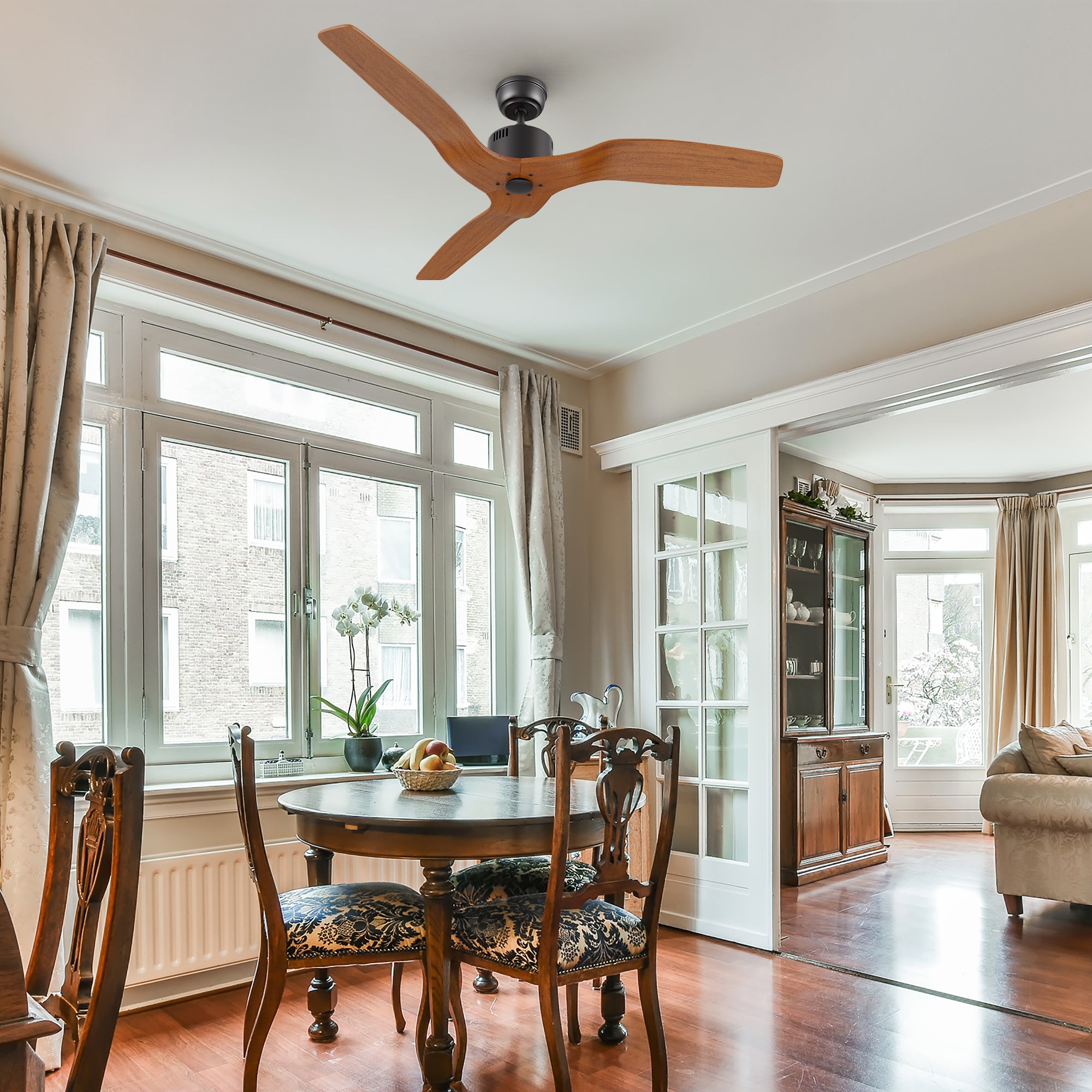 Yarmouth 52-inch black ceiling fan with wood blades, installed in a rustic-style living room featuring wooden floors, dining furniture, and natural lighting.