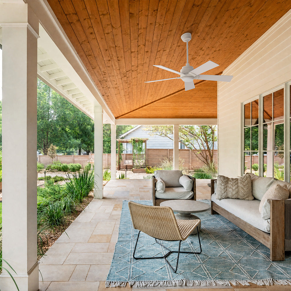 Smafan Aspen 48 inch white outdoor ceiling fan with light installed on a wood paneled covered patio ceiling with modern lounge seating.