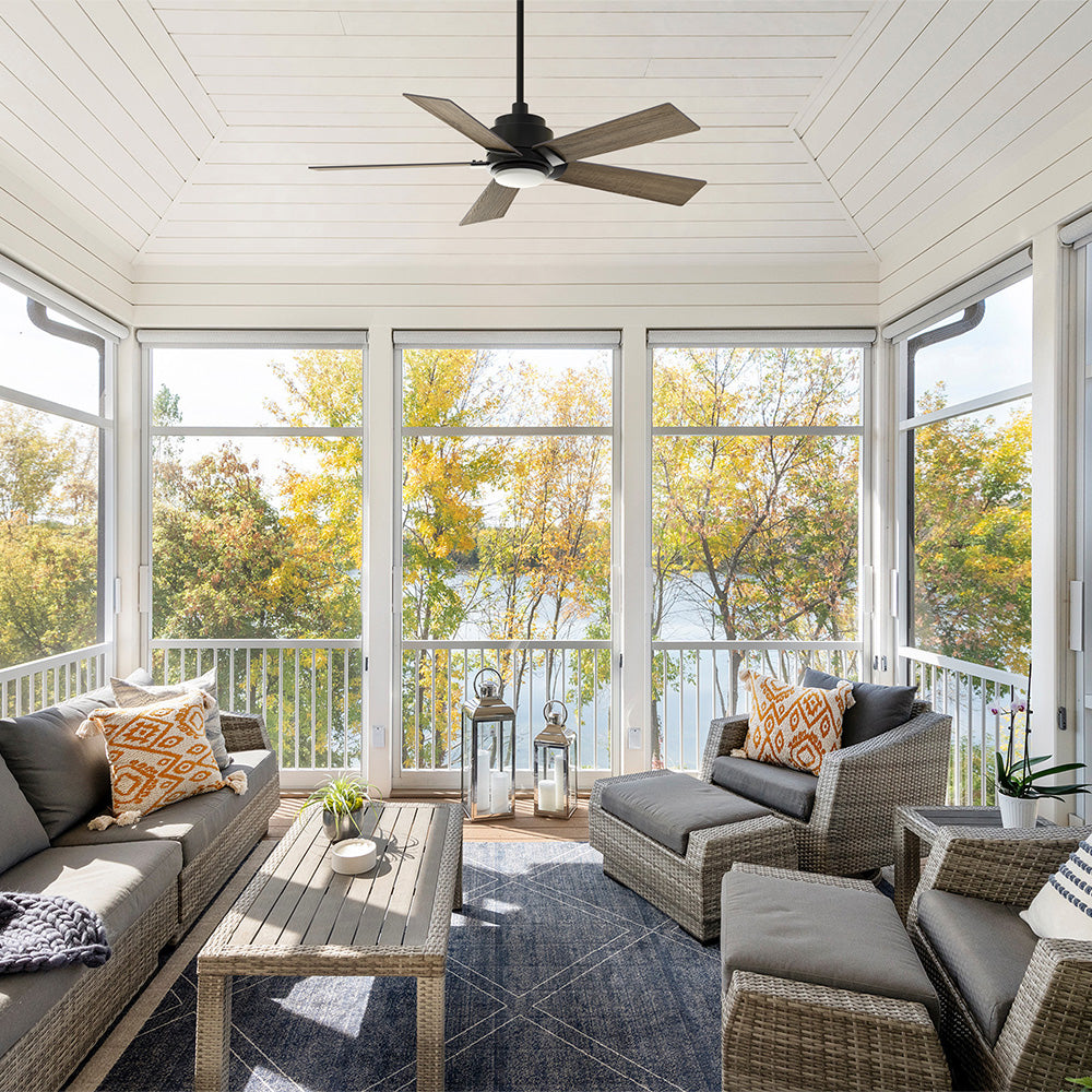 Smafan Aspen modern 5-blade outdoor ceiling fan with downrod and light installed in a screened sunroom overlooking a lake, featuring vaulted white ceilings and wicker lounge seating.