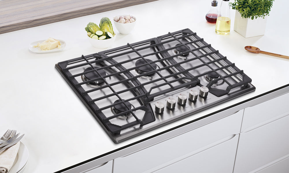 A gas cooktop with three cast-iron grates in the minimalism-style kitchen counter.