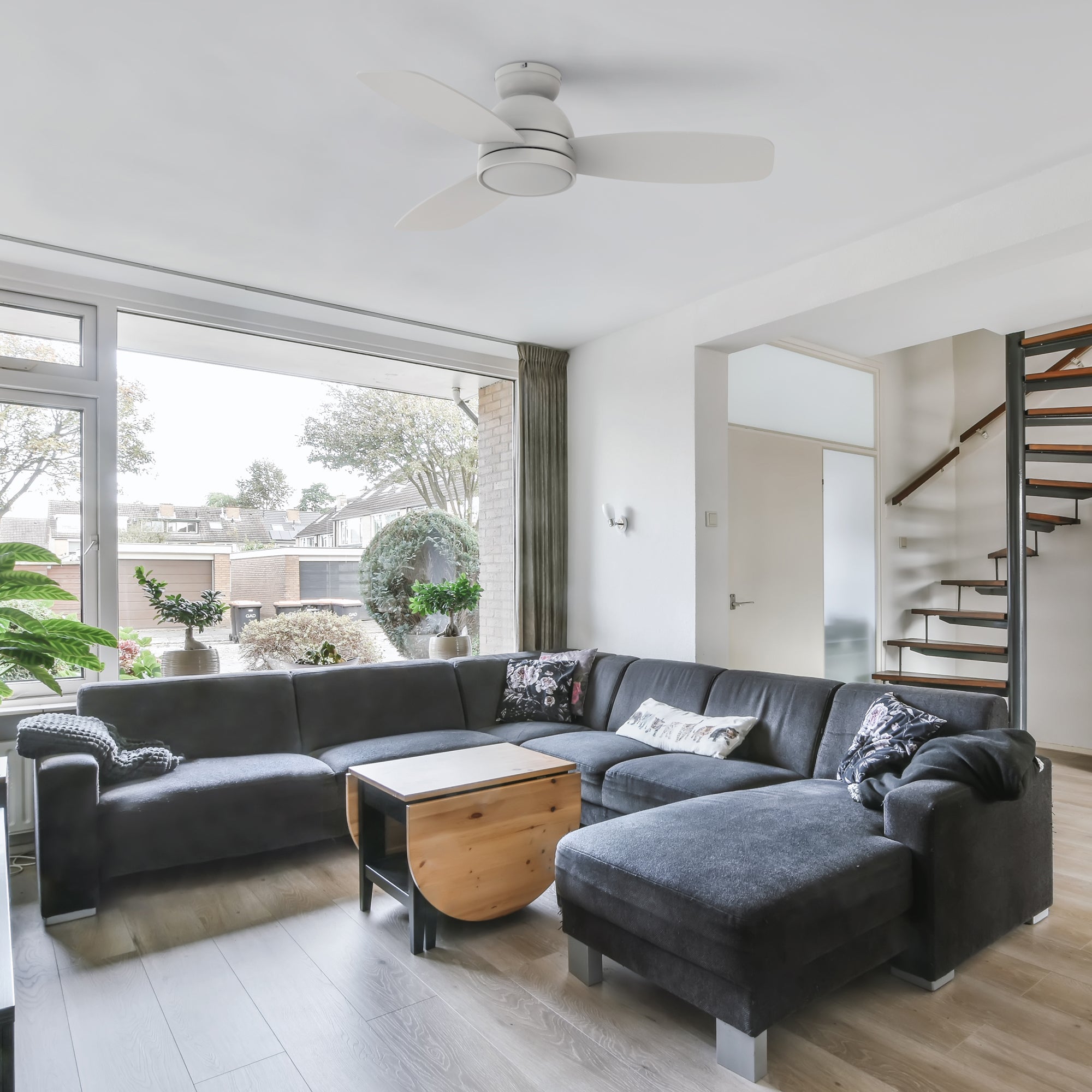 44-inch low profile white ceiling fan with light in modern living room. Paired with a dark grey coral down long sofa, this living room looks more spacious.