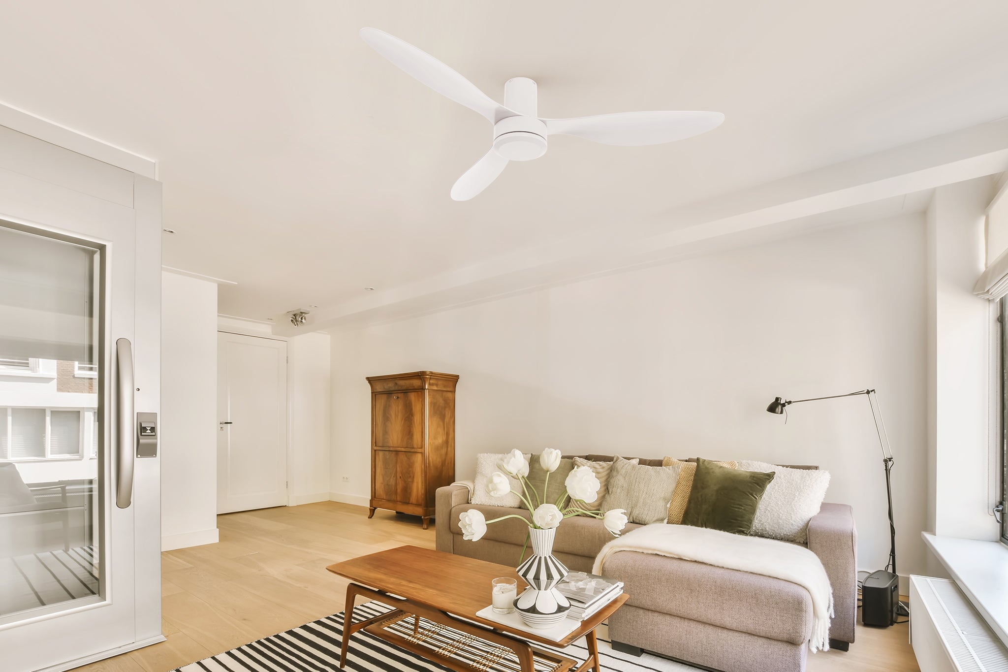 White flush mounting ceiling fan matches with creative white vases, milk tea sofas, and deep wood grain lockers make the living room feel very modern.