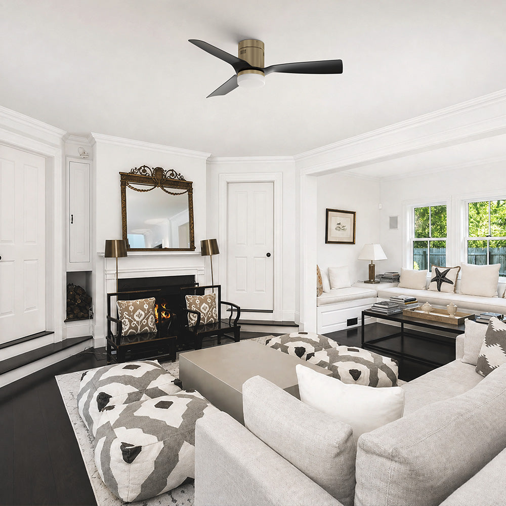 Smafan Striver 52 inch low profile black and gold ceiling fan with LED light installed in a modern living room. The flush mount three-blade ceiling fan features a brushed gold motor housing with black blades, complementing the bright contemporary interior with a fireplace, neutral furnishings, and open-concept layout, delivering quiet, energy-efficient airflow for low ceilings.