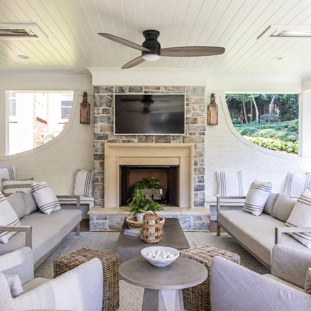 Smafan Trendsetter 60 inch rustic flush mount outdoor ceiling fan with light and weathered wood blades installed on a covered patio with stone fireplace and sectional lounge seating.