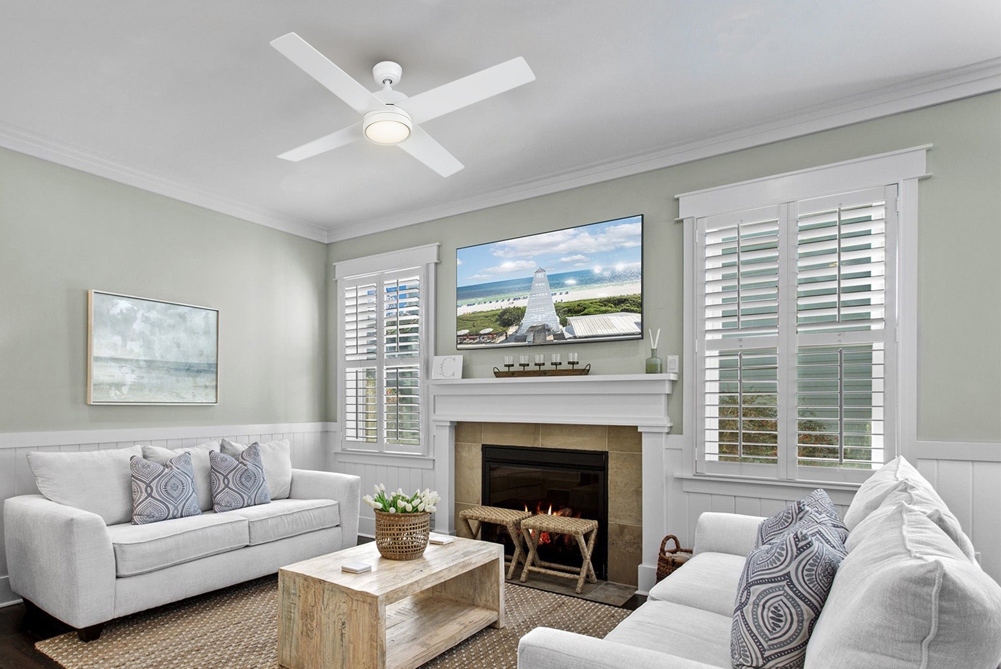 A 52-inch Rossendale white ceiling fan with LED light is prominently featured in a rustic-style living room, which includes a fireplace, television, and white couches with patterned pillows.