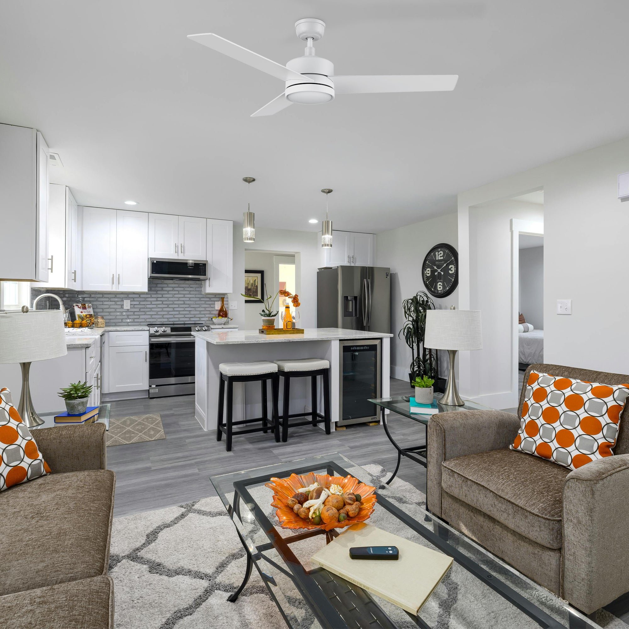 52-inch Louy modern white ceiling fan with integrated LED light and wall switch, installed in a bright, open-concept living room and kitchen featuring neutral tones and contemporary decor. 