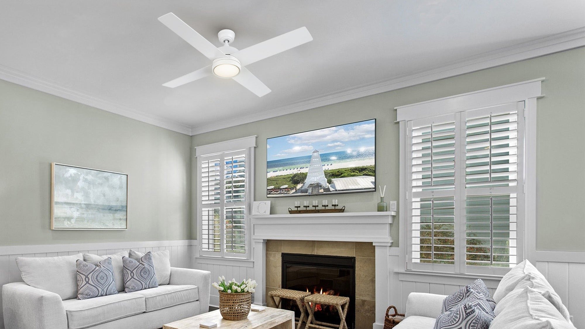 A 52-inch Rossendale white ceiling fan with LED light is prominently featured in a rustic-style living room, which includes a fireplace, television, and white couches with patterned pillows.