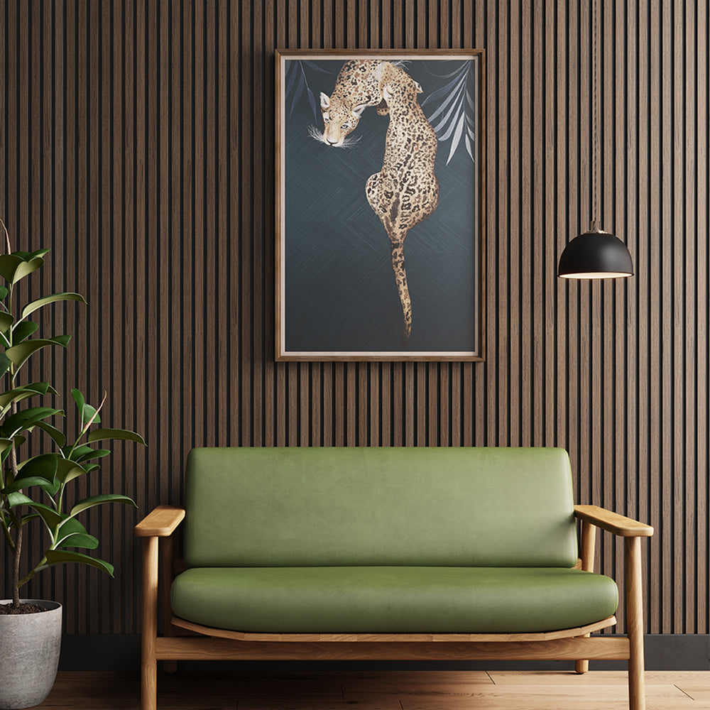 American Dark Walnut Acoustic Slat Wood Wall Panel placed behind a green cushioned sofa chair and a framed leopard artwork, creating a bold, artful sitting area.