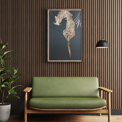 American Dark Walnut Acoustic Slat Wood Wall Panel placed behind a green cushioned sofa chair and a framed leopard artwork, creating a bold, artful sitting area.