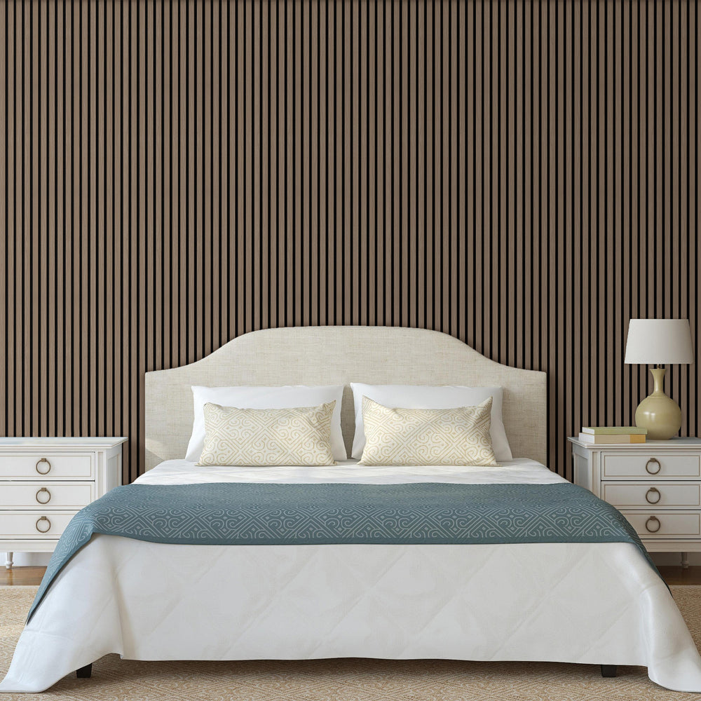Modern bedroom featuring a wall covered with American natural walnut acoustic slat wood panels with black felt, complemented by a bed with white linens and a blue throw blanket, along with a bedside lamp and cabinet.