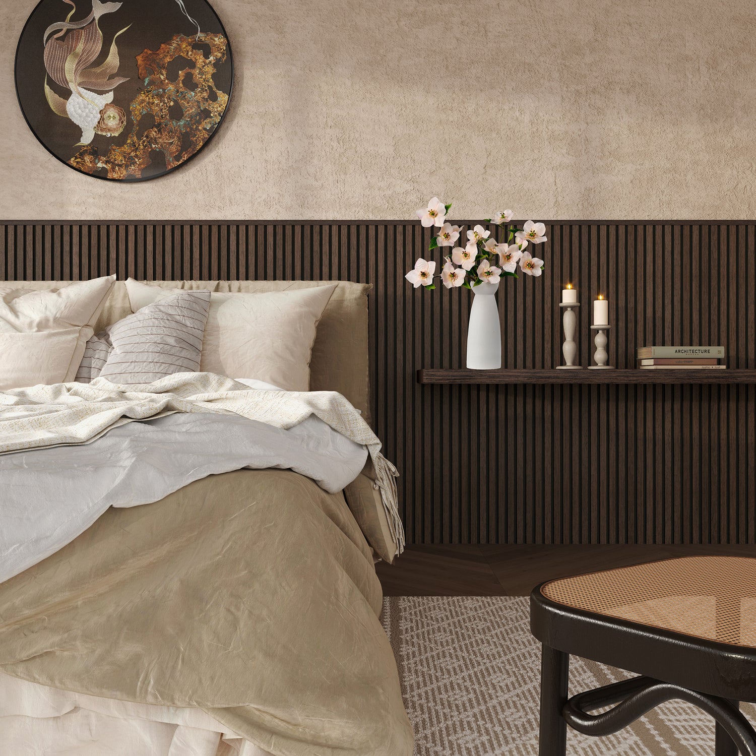 Modern cozy bedroom with a beige and taupe bedding set, featuring a textured wood slat accent wall in dark walnut finish. A floating shelf above the bed holds a minimalist white vase with pink blossoms, two lit candles in sculptural holders, and a small book. The room also includes a round wall art piece with abstract koi fish design, a woven rug, and a cane-seated chair in the foreground, creating a warm and serene ambiance.