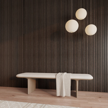 Minimalist interior with American Smoked Walnut acoustic slat wood wall panels, a light wood bench draped with a textured throw, and three modern round paper pendant lights, creating a warm, refined contrast against the dark wall.