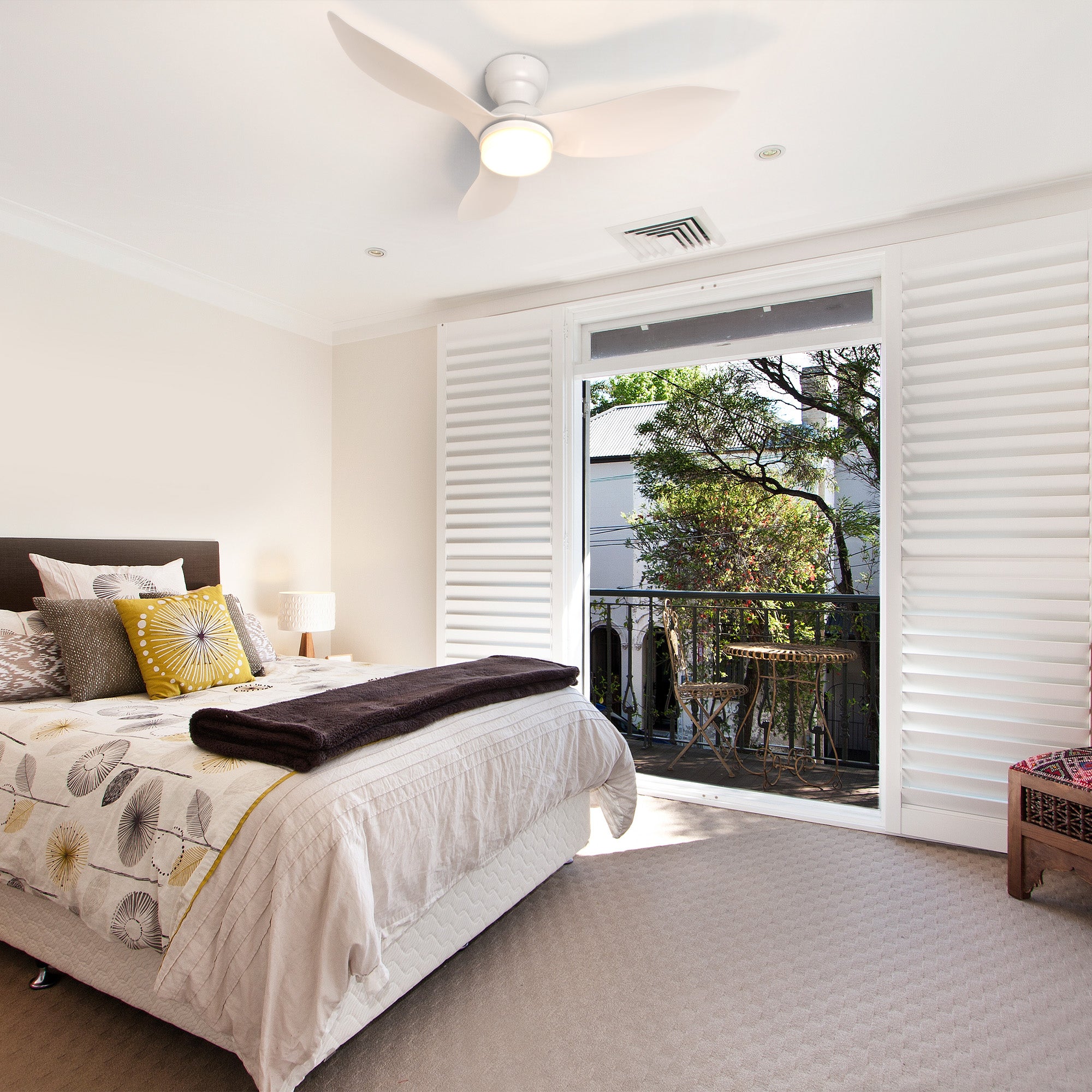 Annecy 45-inch white flush mount ceiling fan with LED light installed in a cozy bedroom featuring natural light, balcony view, and modern decor. 