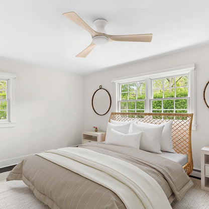White flush mount 3-blade wood ceiling fan with LED light installed on the ceiling of a bright modern bedroom. 