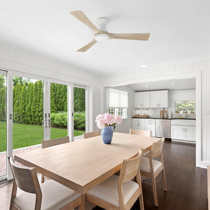 Antrim white flush mount 3-blade wood ceiling fan with LED light installed on the ceiling of a modern dining room and kitchen area. 