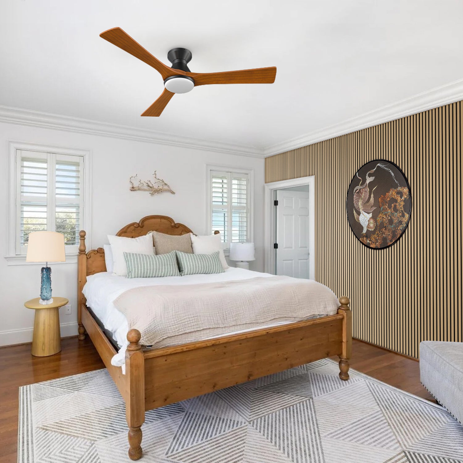 Chic bedroom featuring an Antrim flush-mount ceiling fan with wood blades, a table lamp, and natural walnut acoustic wall panels with art. A blend of functionality and design.