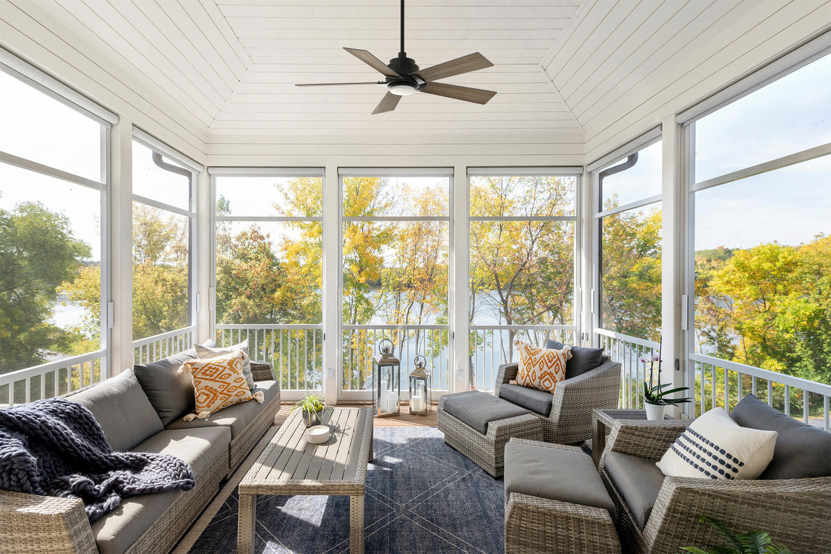 Smafan rustic outdoor ceiling fan with downrod and light installed in a screened three-season sunroom with wicker patio seating overlooking a lake.