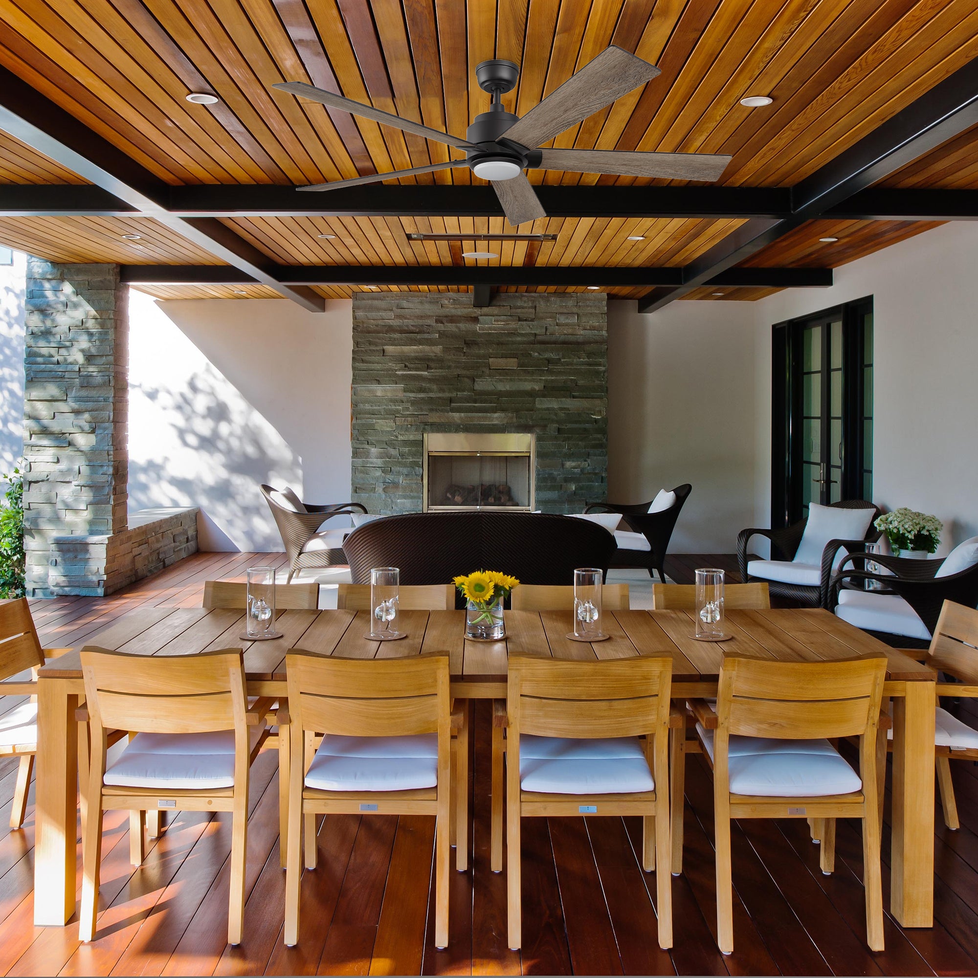 Stylish covered patio featuring the Aspen smart ceiling fan with black blades and an integrated LED light, perfect for outdoor dining areas. 