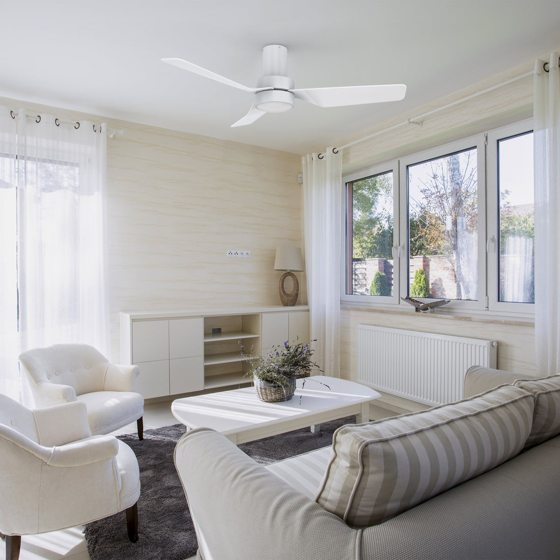A modern and minimalist living room featuring the Barnet 44-inch flush mount smart ceiling fan in a sleek white finish. The fan has three blades and an integrated LED light, providing both illumination and air circulation. Controlled via remote, it seamlessly blends with the bright and airy decor of the space.
