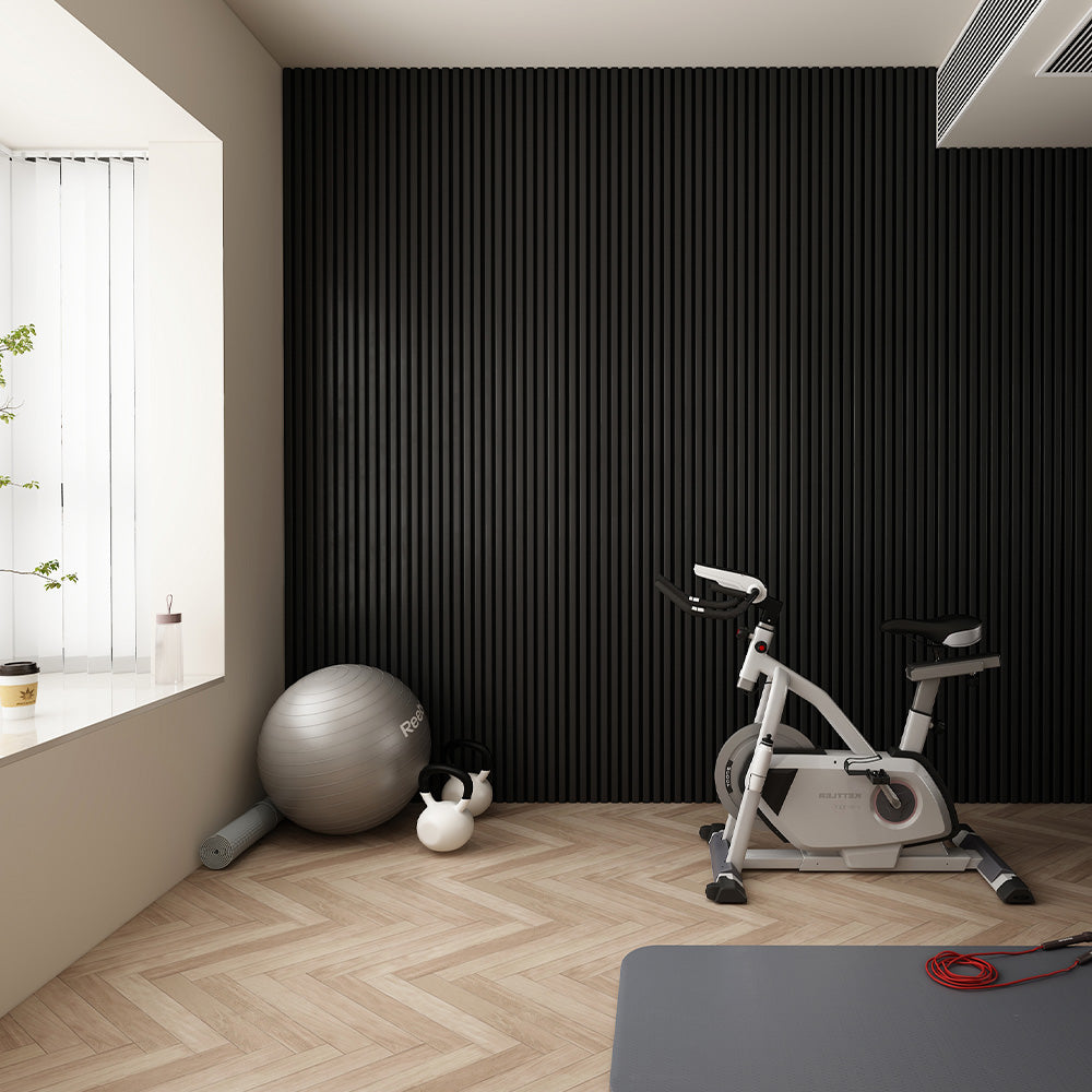 Home gym space featuring black matte acoustic slat wall panels, with exercise equipment and a sleek, minimalist interior.