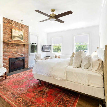 Scandinavian-style bedroom with the Carro Smafan Rossendale 52-inch ceiling fan in gold, mounted above a white bed and red rug. 