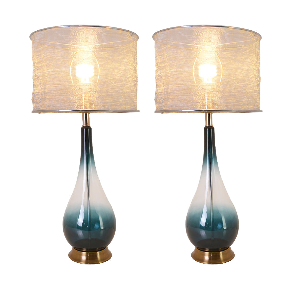 A pair of Carro Smafan 30-inch Tulip Big table lamps with Dark Green Ombre finish and Translucent Silver shades, placed on nightstands in a bedroom. The lamps provide warm lighting, enhancing the room&
